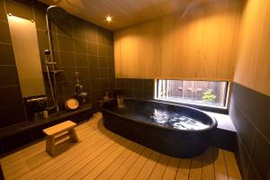 Una gran bañera negra en un baño con ventana en ブランシエラ ヴィラ 明日香, en Asuka
