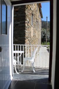 uma cadeira branca sentada num alpendre ao lado de um edifício em Casa do Avô em Vasco Esteves de Baixo