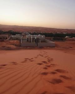 a building in the desert with footprints in the sand at Private Sand Bond in Al Raka