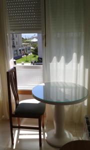 a glass table and a chair and a window at Hostal Casa Maria in Portonovo