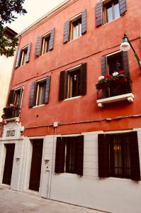 un gran edificio rojo con ventanas y flores en las ventanas en Ca' del Pittor Apartments, en Venecia