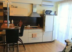 a kitchen with white cabinets and a table and a sink at Nidos Poilsine Studio in Nida