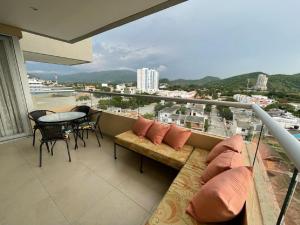 a balcony with a couch and a table and chairs at Rodadero Sur Confortable in Santa Marta