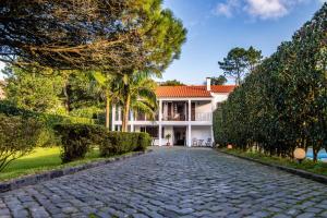 a cobblestone driveway in front of a house at Casa do Pinheiro with shared swimming pool in São Vicente Ferreira