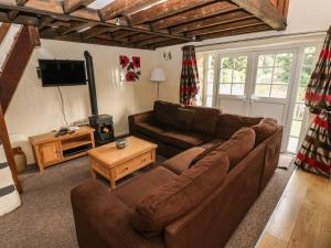a living room with a couch and a television at Rafters Cottage in Walton East