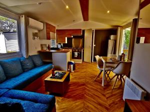 uma sala de estar com um sofá azul e uma cozinha em Aventura 3 em Gastes