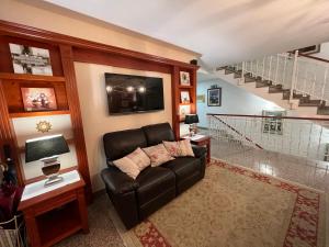 - un salon avec un canapé en cuir noir et des escaliers dans l'établissement Nature Hotel Lukanc, à Bled