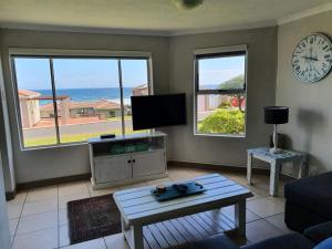 a living room with a couch and a tv and two windows at Hermanus Beach Club in Hermanus