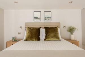 a bedroom with a white bed with gold pillows at Museum Apartments in Edinburgh