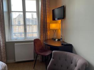 um quarto com uma secretária, uma cadeira e uma televisão em Auberge du Chasseur em Grosrouvre