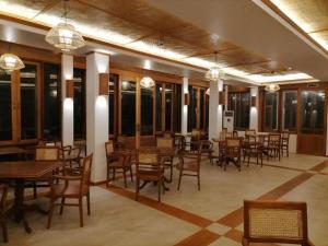 a dining room with tables and chairs and windows at Bagan Cottage Boutique Hotel in Nyoungoo