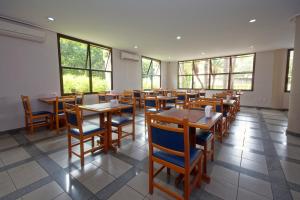 restauracja z drewnianymi stołami i krzesłami oraz oknami w obiekcie Fênix Hotel Limeira w mieście Limeira
