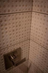 a toilet paper dispenser on a tiled wall at Hotel Broad Ripple in Indianapolis