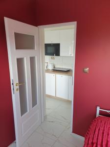 an open door to a kitchen with red walls at Apartament Centrum in Ustroń +1 photo