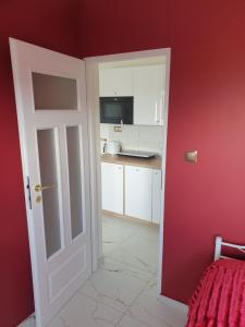 an open door to a kitchen with red walls at Apartament Centrum in Ustroń