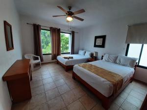 a hotel room with two beds and a ceiling fan at Villas Mayaluum Cozumel in Cozumel