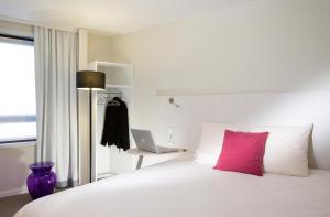 - un lit blanc avec un oreiller rose et un ordinateur portable dans l'établissement ibis Styles Lille Centre Gare Beffroi, à Lille