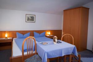 a bedroom with a blue bed with a table and chairs at Pension Fundus in Pfunds