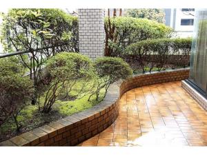 cortile con muro di mattoni, alberi e cespugli di THE TORII - Vacation STAY 68438v a Kumamoto