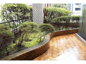 a courtyard with a brick wall and trees and bushes at THE TORII - Vacation STAY 68438v in Kumamoto
