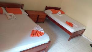 two beds with orange and white sheets in a room at HOTEL EL CAMINANTE DEL LLANO in Pore