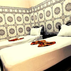 two beds in a room with white sheets at Hotel Zagora in Marrakesh