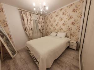 a bedroom with a bed with floral wallpaper and a chandelier at The Hedgehog Boutique House & Garden in Cluj-Napoca