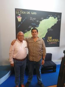 dos hombres parados uno al lado del otro delante de una señal en Hostal La Casa de Luis en Puerto Baquerizo Moreno