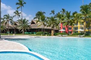 a swimming pool in front of a resort with palm trees at Caribe Deluxe Princess - All Inclusive in Punta Cana