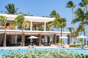 a beach with a pool, chairs, and umbrellas at Tropical Deluxe Princess - All Inclusive in Punta Cana