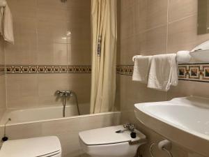 a bathroom with a toilet and a tub and a sink at Hotel Condal in Salamanca +32 photos
