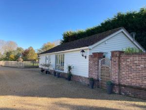 a small white house with a brick wall at The Oaks, Luxury 2 bedroom cottage in a peaceful location in Haughley