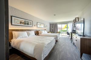 ein Hotelzimmer mit 2 Betten und einem TV in der Unterkunft Hôtel Versō in Magog-Orford