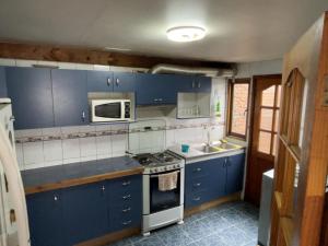 a kitchen with blue cabinets and a stove top oven at Casa Centro Villarrica in Villarrica
