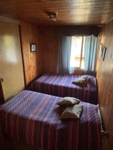 1 dormitorio con 2 camas en una habitación de madera en Casa Centro Villarrica en Villarrica