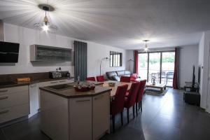 布里昂松SUPERB apt with BALCONY in BRIANÇON的厨房以及带桌子和红色椅子的客厅。