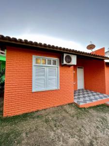 uma casa vermelha com uma janela e uma porta em Sunshine Inn Centro em Cumbuco