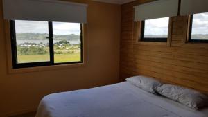 a bedroom with two windows and a bed with white sheets at CASAS Y CABAÑAS CUMBRES DEL SOL in Castro +135 photos