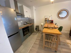 La cuisine est équipée d'une table et d'un réfrigérateur en acier inoxydable. dans l'établissement Nouveau F2 au calme proche Paris, à Montigny-lès-Cormeilles