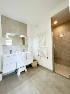 La salle de bains est pourvue d'un lavabo blanc et d'un miroir. dans l'établissement Spacieux appartement neuf de standing Hyper Cosy, à Larmor-Plage