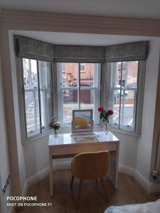a desk in a room with windows with a laptop on it at GS - Luxury, modern town centre, 2 beds, free parking for one vehicle in Stratford-upon-Avon
