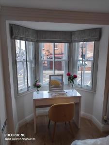 a desk in a room with windows with a laptop on it at GS - Luxury, modern town centre, 2 beds, free parking for one vehicle in Stratford-upon-Avon +2 photos