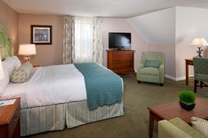 a hotel room with a bed, chair and television at Sea Crest Beach Hotel in Falmouth