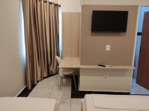 een kamer met een bureau en een televisie aan de muur bij Liv Hotel in Pôrto Ferreira
