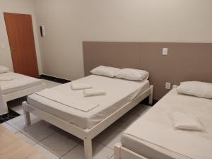 Liv Hotel في بورتو فيريرا: سريرين في غرفة مع ملاءات بيضاء ومناشف