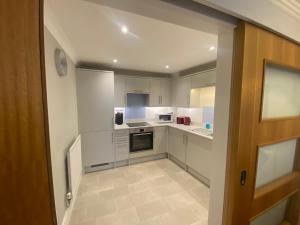 a small kitchen with white cabinets and appliances at GS - Luxury, modern town centre, 2 beds, free parking for one vehicle in Stratford-upon-Avon