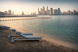 two lounge chairs on the beach with a city skyline at Dukes The Palm Dubai Hotel in Dubai +102 photos