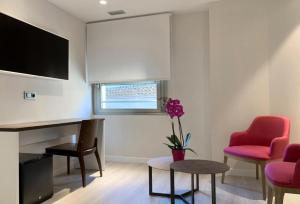 Hotel Remigio في توذيلا: غرفة معيشة مع مكتب وكراسي حمراء