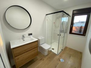 a bathroom with a toilet and a sink and a mirror at apartamento chousa bajo in Sigüeiro