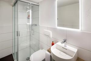 a white bathroom with a sink and a shower at Hotel Schweizerhof in Wetzikon